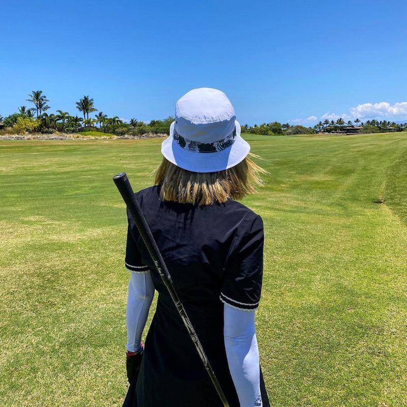 Woman looks out to golf course with ocean visible in the distance