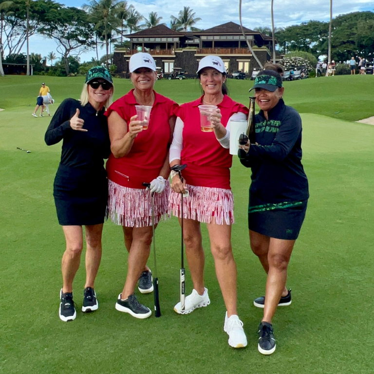 4 women pose outdoors on putting green with tequila in hand 