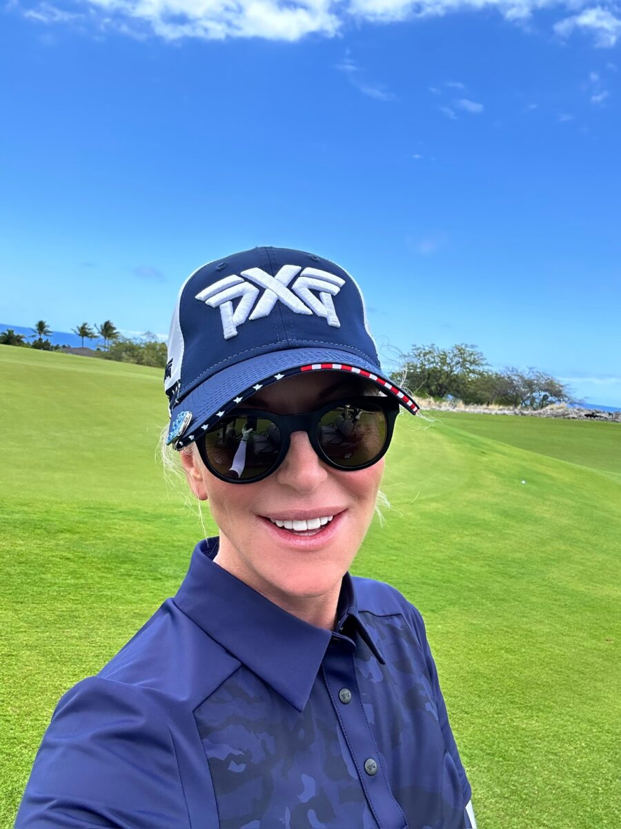 Woman in navy baseball cap takes a selfie on the golf course