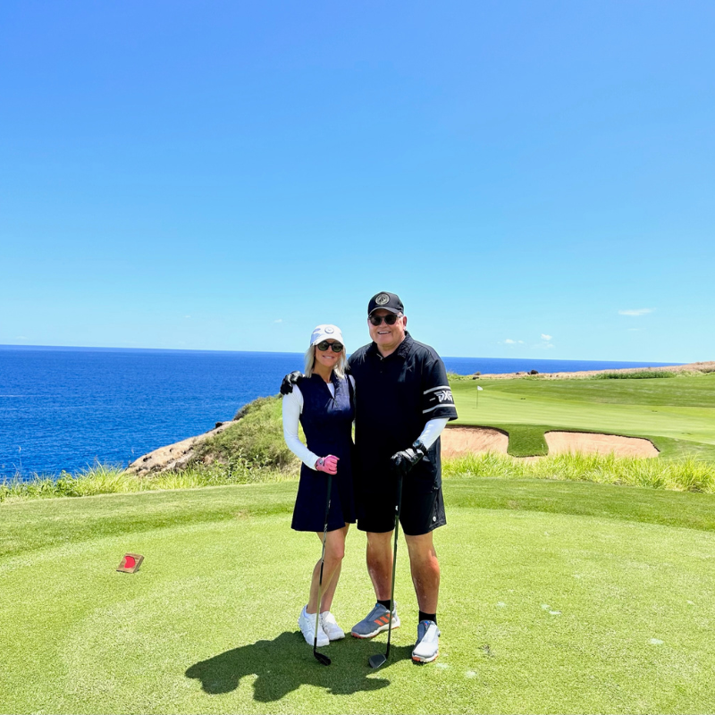 Man and woman pose for a photo on a golf course
