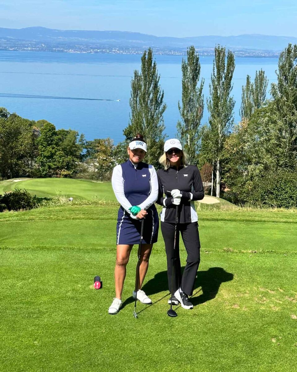 Two women pose on golf course with ocean view 
