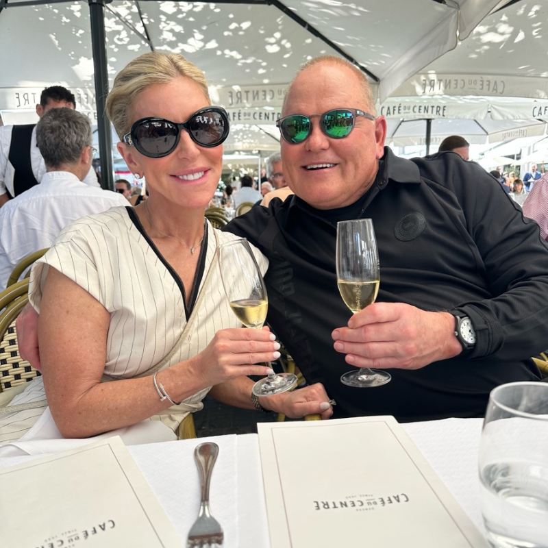 Man and woman dine outside in a tent, cheers champagne