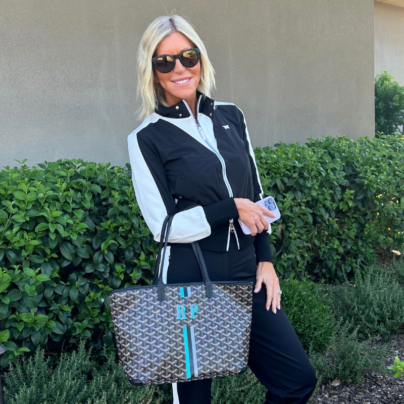Woman in black and white tracksuit poses with purse