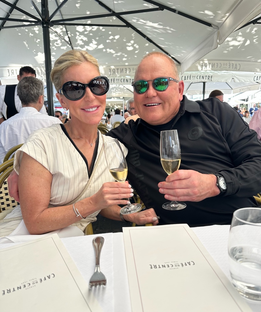 Man and woman dine outside in a tent, cheers champagne